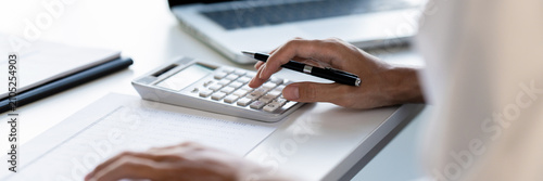 Foto accountant using calculator and reviewing charts for tax adjustment on corporate
