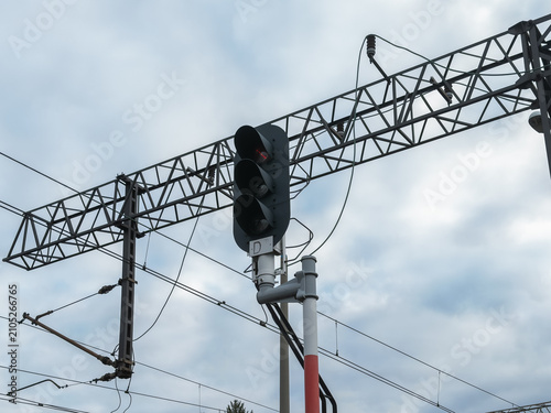 Bild auf Leinwand A railway signal light mounted on a steel gantry under a cloudy sky, controlling