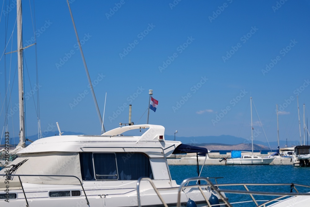 Fototapeta premium White Motor Yacht Moored In Marina Under Blue Sky
