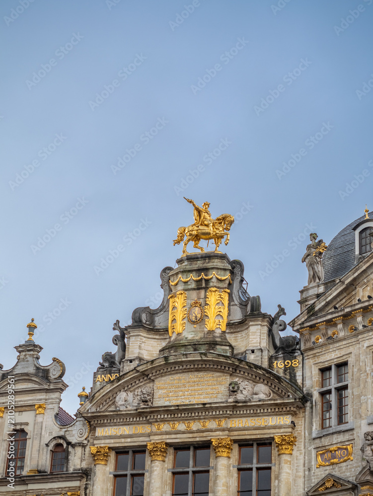 Fototapeta premium Ornate Baroque guild house facade with gilded decoration at the historic Grand Place under dramatic cloudy sky