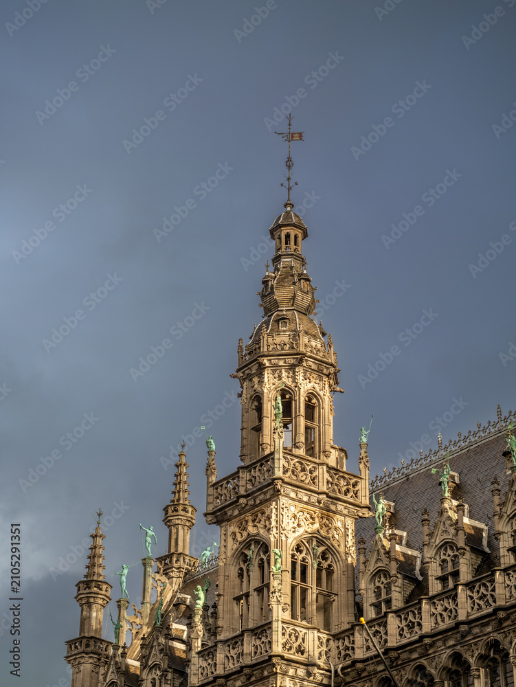 Fototapeta premium Historic Gothic tower viewed from Grand Place against dramatic overcast sky.
