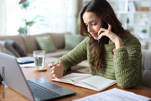 Quadro su tela Stressed teleworker talking on phone checking agenda