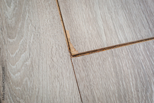 Foto Damaged laminate flooring with chipped edge, swollen joint, visible wear from mo