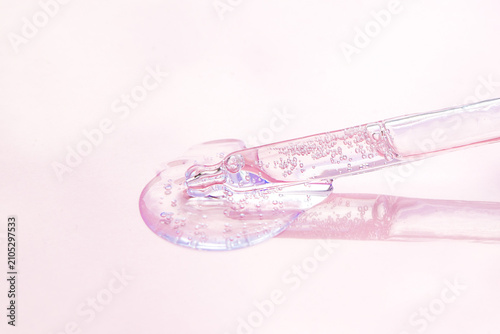 Pink cosmetic serum with glass dropper and bubbles on pastel background for skincare and beauty