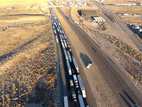 Fotografía Aerial drone photograph of heavy truck traffic on a major interstate highway with long line of freight vehicles transporting cargo