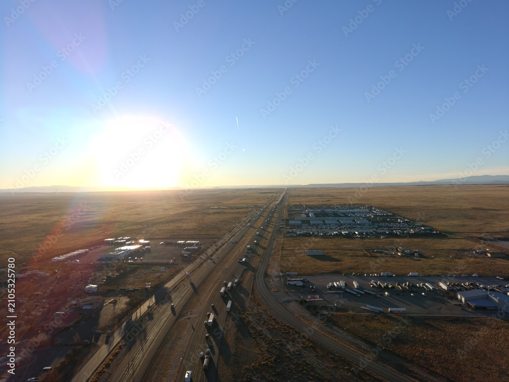 Fototapeta premium High resolution aerial drone view of a major interstate highway crossing an open desert landscape during sunset. Commercial transportation, freight logistics, road infrastructure, travel and supply ch
