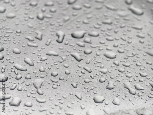 Close-up of fresh water drops on a smooth grey surface.
