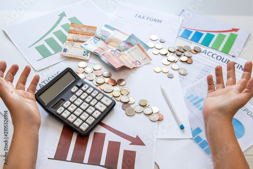 Tableau sur toile A businessman's hands, with a frustrated sign, are spread over financial documents and graphs on an office desk