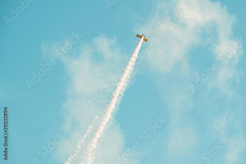 Portugal Oeiras Air Show. A plane flies high in the sky, making a sharp turn while leaving smoke trails behind. This event takes place during an air show near the city on a clear day.