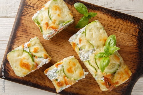 Close-up of sliced ​​zucchini roll stuffed with salmon and cream cheese on a wooden board on the table. Horizontal top view from above