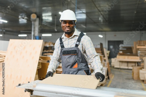 Foto Furniture maker preparing wood panel on cnc machine in factory