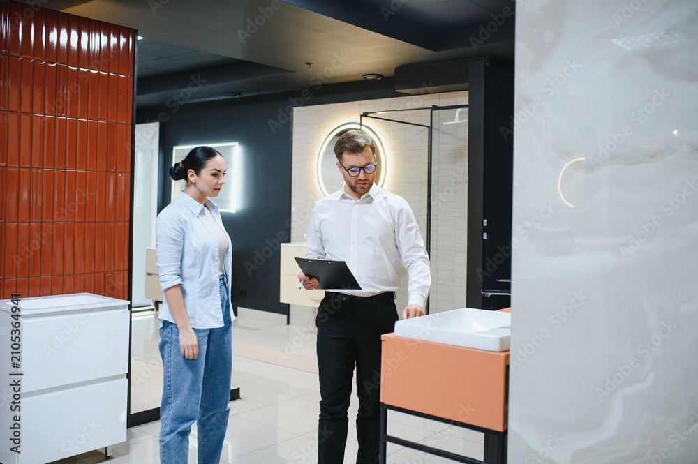 Fototapeta premium Shop assistant showing a sink to a customer in a bathroom furniture store