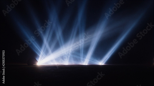 bright blue spotlights beam projection on dark stage floor