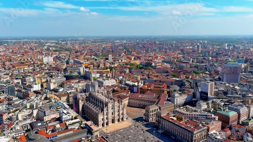 Aerial view of Milan Cathedral and Piazza del Duomo in Italy, with people on the square, the Galleria Vittorio Emanuele II dome, the Royal Palace, Torre Velasca and rooftops of the centre.