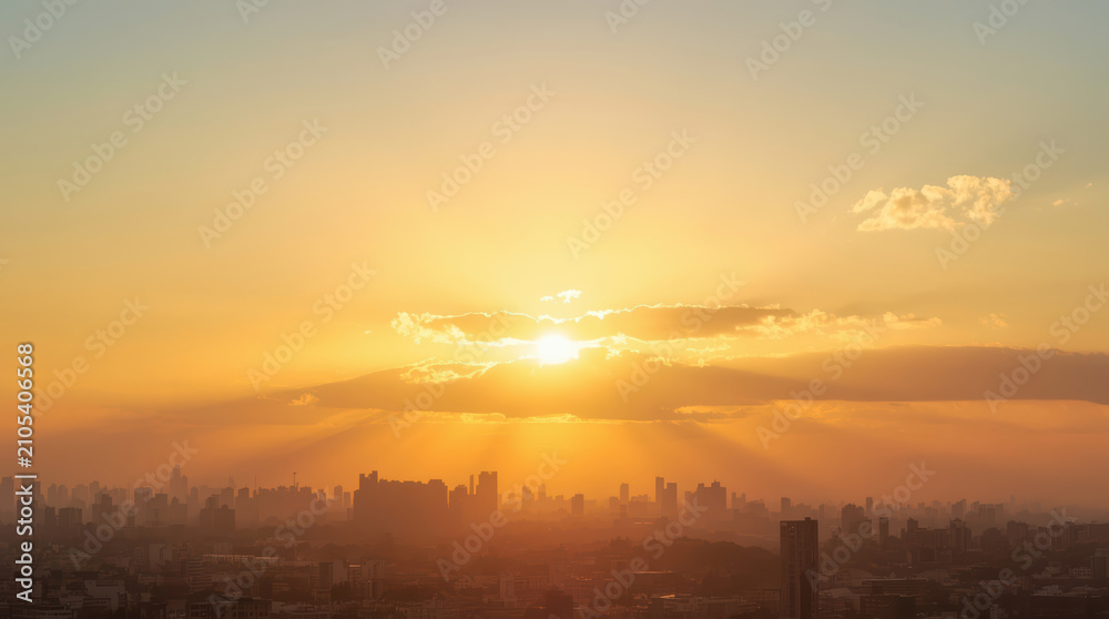 Fototapeta premium Golden sunrise over urban skyline with warm light rays and hazy cityscape