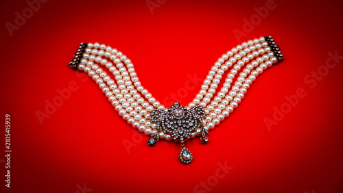 Elegant Multi-Strand Pearl Necklace with Crystal Pendant on Vibrant Red Background
