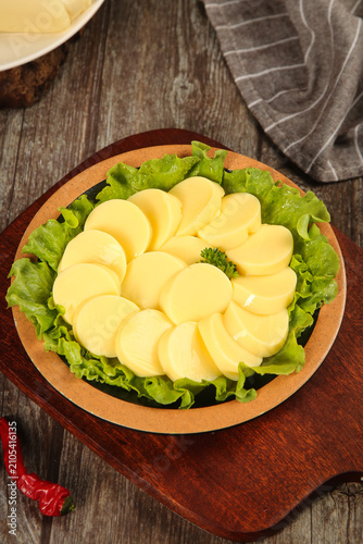 Fresh Sliced Potatoes Arranged in Flower Pattern on Lettuce Bed in Rustic Wooden Bowl