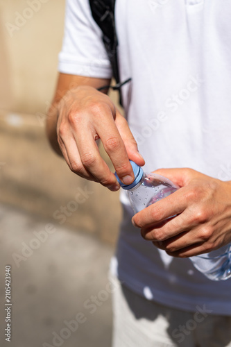 Fotografia A close-up shot shows a person closing a clear plastic bottle with a tethered blue cap