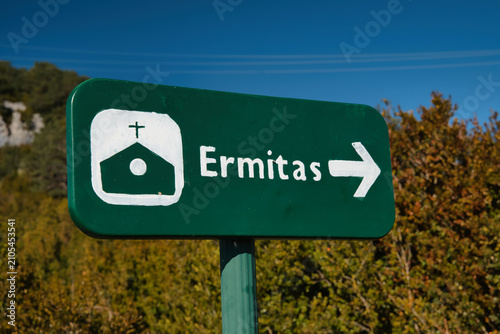 It displays a green informational sign indicating the route to the Chapel Trail 
in Tella, Huesca, featuring a chapel symbol and a yellow arrow pointing to the left.
