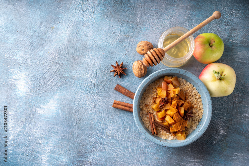 Obraz premium Autumn tasty breakfast Oatmeal Porridge with Apple and Cinnamon in bowl, top view. Healthy balanced morning meal, oats with baked apple