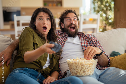 фотографія Couple watching thrilling movie at home, feeling startled