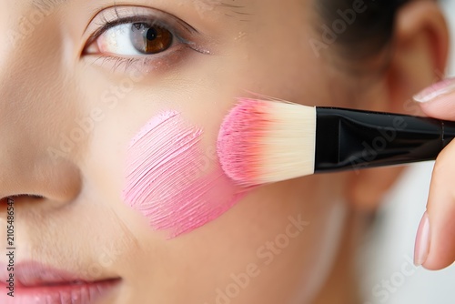 Woman applying blush with makeup brush