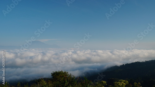 Obraz na płótnie Wide landscape view captures sea of clouds surrounding mountain peak
