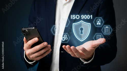 ISO 9001 Quality Management System: A businessman holding a smartphone displays the ISO 9001 certification emblem with a keyhole, symbolizing security and quality standards in business operations.