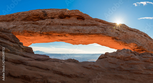 Photos Majestic natural stone arch glows bright orange under clear blue sky with shinin