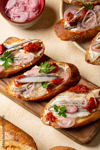 Seafood Sandwiches, appetizers or bruschetta with red onions and marinated anchovies, sun dried tomatoes, soft cheese. Traditional Italian summer snack,  Venice cicchetti. Verical image.