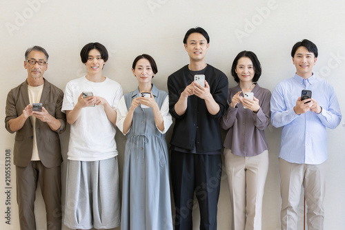 スマートフォンを操作する多世代の日本人グループポートレート