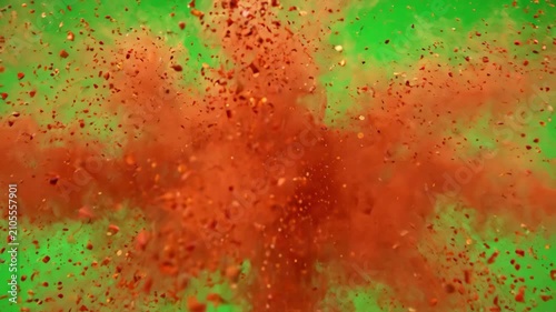 Vibrant red chili powder exploding in a dense cloud against a bright green screen background for easy chroma keying