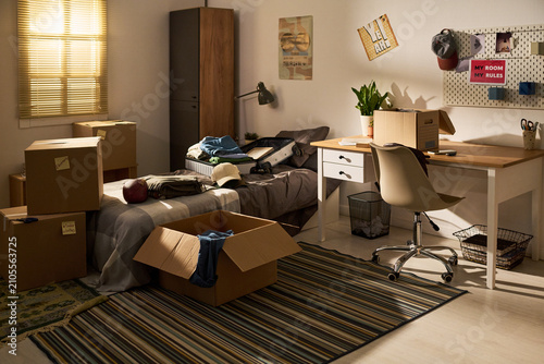 Obraz na płótnie Wide shot of teenager bedroom showing unpacking boxes, packed suitcase, study desk, signaling dorm move in or relocation