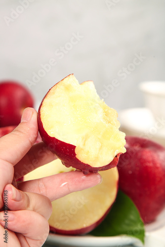 Fotografie Fresh Red Apple Bite - Hand Holding Crisp Fruit Slice with Natural White Flesh