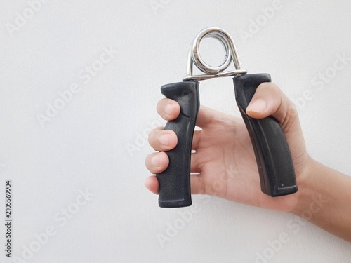 Foto Hand squeezing a black hand gripper for grip strength training and forearm exercise on plain background with copy space