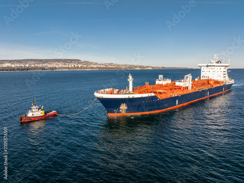 Large oil tanker ship escorted by two tugboats. Concept of maritime transport, global logistics, and international trade.