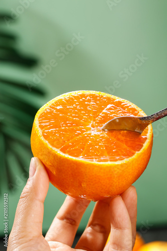 Fresh Orange Half with Spoon in Hand - Citrus Fruit and Healthy Eating Concept
