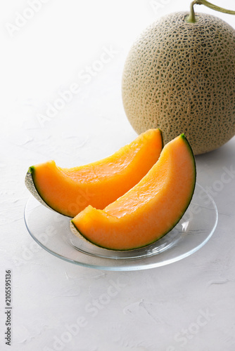 テーブルに置かれた北海道産の赤肉カットメロン　Cut orange flesh Japanese melon on a table, Hokkaido cantaloupe