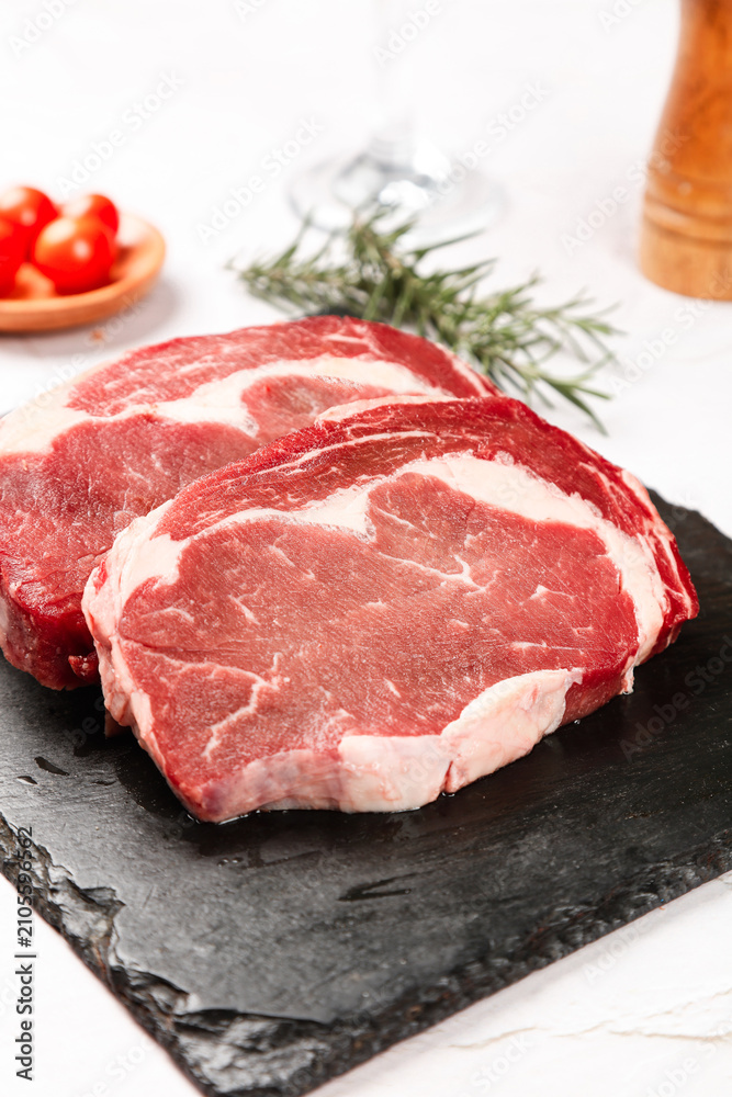 Fototapeta premium Fresh Raw Ribeye Steaks on Slate Board with Rosemary - Premium Thick Cut Beef Ready for Cooking