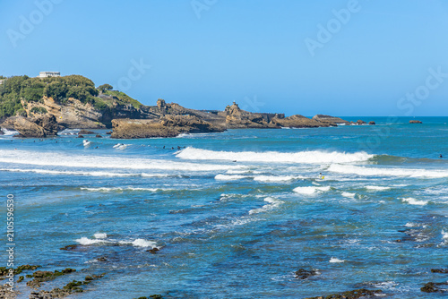 View of turquoise ocean water and foaming surf washing over dark rocky reefs along the ruggged Biarritz coast
