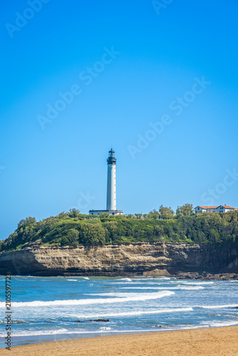 Distant Biarritz Lighthouse overlooking gentle surf breaking on the sandy beach in France