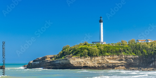 Panoramic view of the Biarritz Lighthouse atop the rocky headland of Pointe Saint-Martin under a blue cloudless sky in France