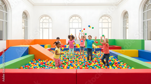 Children joyfully playing in a colorful ball pit indoors with vibrant balls and soft structures