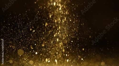 Golden sparkles exploding in dark background. Glitter particles bursting with high-speed motion for celebrations.
