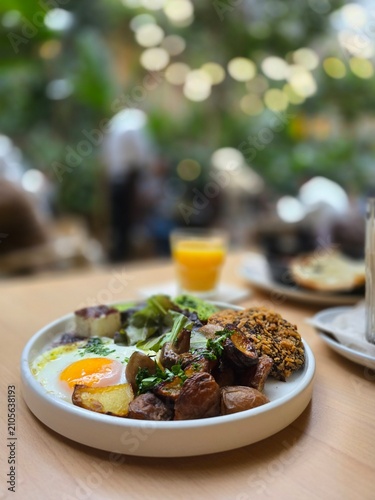 Fotografie Healthy brunch plate with a baked egg and mushrooms in a plant-filled cafe