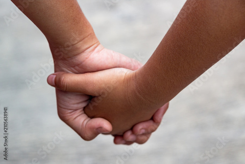 Two children holding hands close up outdoor