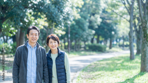 新緑の公園を歩く中高年夫婦