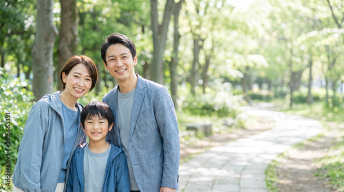 新緑の公園で微笑む父母と小学生の息子