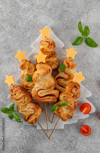 Puff pastry Christmas tree buns with cheese and ham on a marble board. Christmas and New Year appetizer. Top view, copy space.