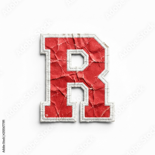 Close-up of a distressed red letter R with frayed white edges, textured surface, studio lighting, neutral background, high contrast.